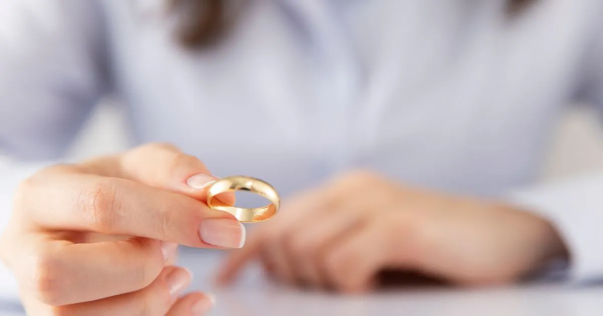 Lady's hand holding a golden ring.